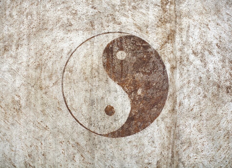 Ein Yin-Yang-Symbol auf einer verrosteten und verwitterten hellen Metalloberfläche.