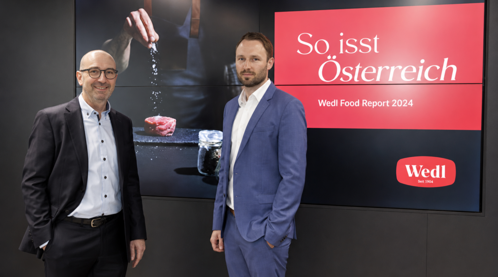 Zwei Männer im Anzug stehen vor einer Präsentationswand zum Wedl Food Report 2024.