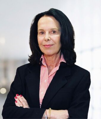 Françoise Bettencourt Meyers im schwarzen Blazer und gestreiften Hemd mit verschränkten Armen