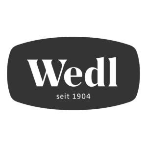 Weißes Wedl Logo auf dunkelgrauem Oval mit dem Schriftzug seit 1904