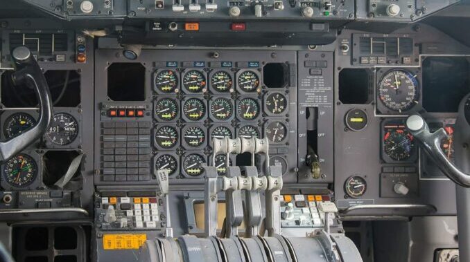 Detaillierte Cockpit-Instrumententafel eines Flugzeugs mit vier Schubhebeln und zahlreichen analogen Anzeigen.