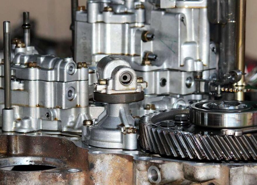 Detaillierte Nahaufnahme metallischer Bauteile, Zahnräder und Ventilblöcke eines zerlegten Fahrzeuggetriebes.