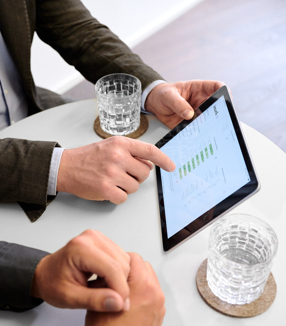 Ein Geschäftsmann deutet auf ein Tablet mit Diagrammen während einer Besprechung.