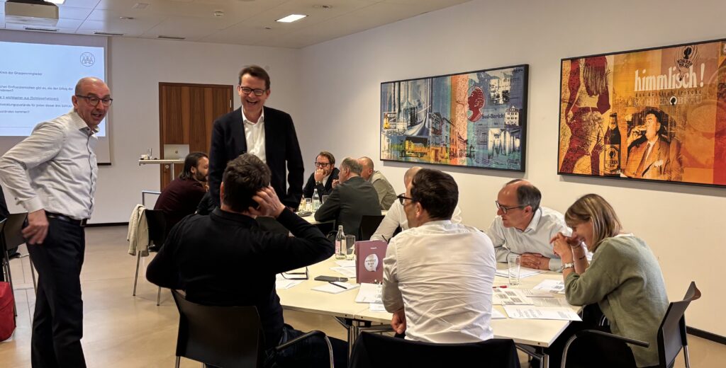 Gruppe von Geschäftsleuten unterhält sich lachend bei einem Workshop in einem Konferenzraum.