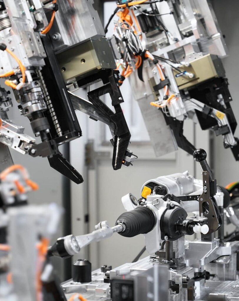 Automatisierte Roboterarme bei der präzisen Fertigung eines Lenkgetriebes in der Industrie.