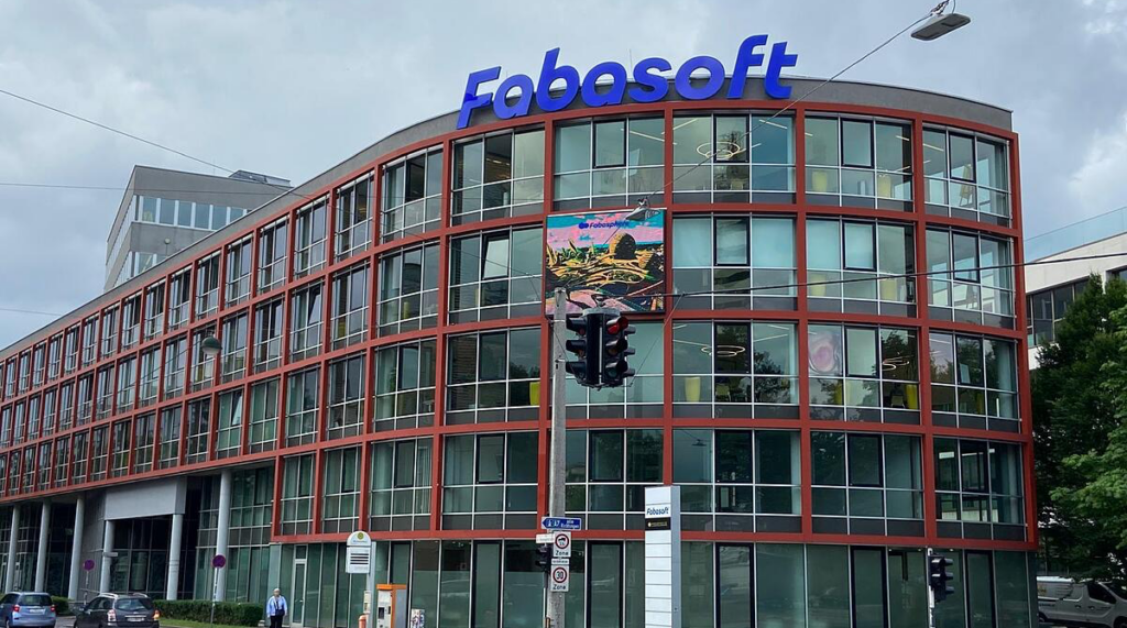 Moderne Fabasoft-Unternehmenszentrale mit rot gerahmter Glasfassade und blauem Logo auf dem Dach.