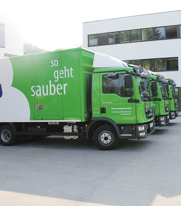 Grüner Lkw mit dem Slogan so geht sauber parkt vor einem modernen Bürogebäude.